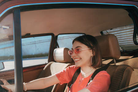 Girl wearing sunglasses sitting behind the wheel in the drivers seatの写真素材