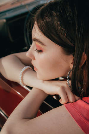 Girl wearing pink clothes sitting the drivers seat at her car