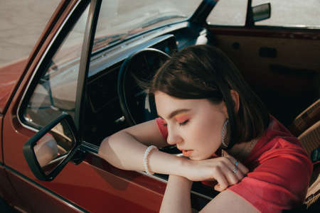Girl sitting the drivers seat at her car and relaxing with closed eyes