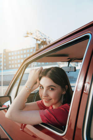 Girl sitting at the car and posing to the camera while spending time at the streetの写真素材