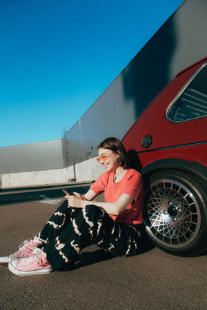 Woman messaging on smartphone at the street, while sitting comfortably on the ground