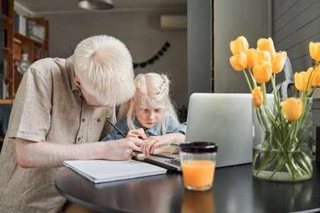 Girl stuck with hard task and preparing homework with caring her bearded fatherの写真素材