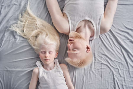 Man laying with his cute blonde daughter together at the bed with closed eyesの写真素材