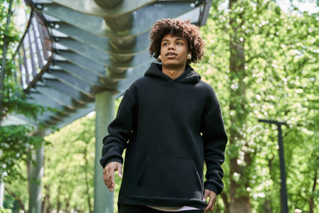 Man wearing earphones while walking at the summer park around the green natureの写真素材