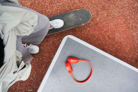 Teenager standing with one leg at the skate and preparing to taking his headphonesの写真素材