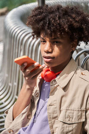 Man recording voice message for somebody while sitting at the bench and working