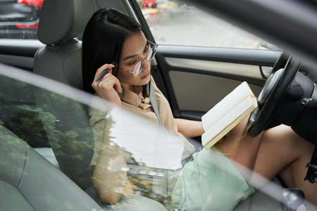 Woman sitting behind the wheel and looking at the road while relaxingの写真素材