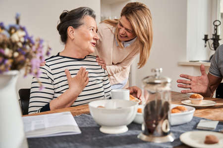 Woman sitting at the table and talking with friendly nurse in the retirement homeの写真素材
