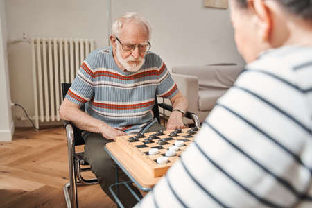 Aged couple playing at the checkers at the nurse houseの写真素材