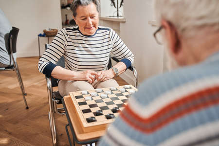 Seniors couple playing checkers at nurse home togetherの写真素材