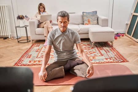 Man practicing yoga and sitting on lotus position at the mat with eyes closedの写真素材