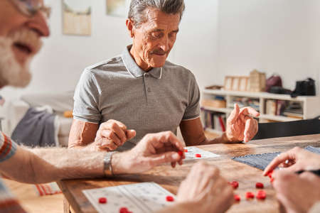 Senior friends having fun with table bingo game together