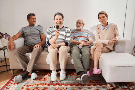 Woman singing at the karaoke while spending time with her friends and caregiver