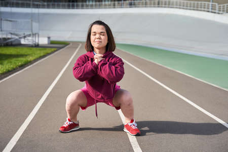 Dwarf woman with dark hair doing slopes and another physical activity outdoorsの写真素材