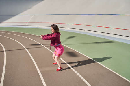 Midget woman squatting at the stadium outdoor during the morningの写真素材