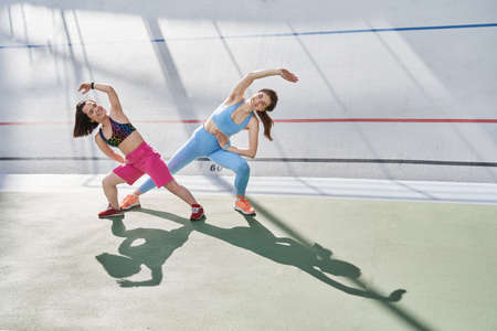 Diverse girls engaged in the stadium, while doing slopes with pleasure smiles