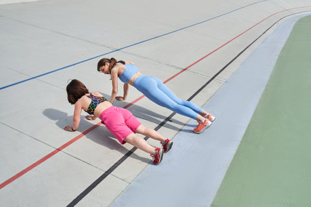 Diverse girls in fashion sporty outfit doing intense exercise at outdoor stadium