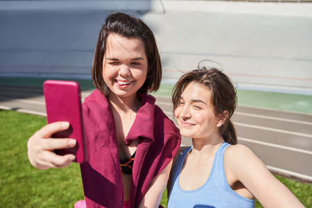 Woman in sportswear relaxing after a workout or run and taking selfies on her smartphoneの写真素材