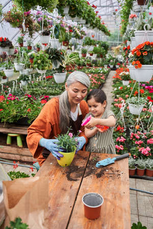 Grandmother looking with tenderness at her little child while she watering plants