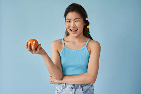 Asian woman with happy face holding citrus fruit and smiling