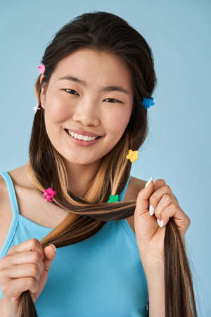 Girl smiling cheery while holding her hair with cute hairpins and posing