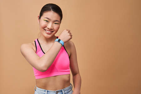Woman showing hand with smart watch to the camera while standing and smiling