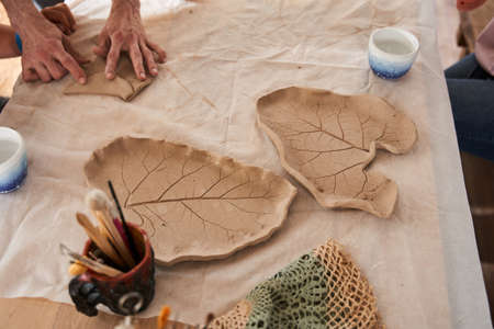 Two clay plates at the shape of the leaf standing at the table and being readyの写真素材