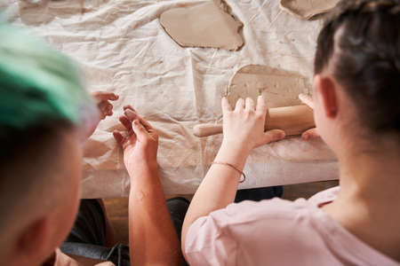 Girl with special needs holding rolling pin and giving shape for clay at the master classの写真素材