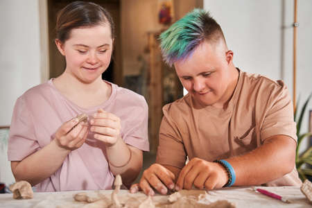 Couple of the down syndrome people feeling happy and working with clayの写真素材