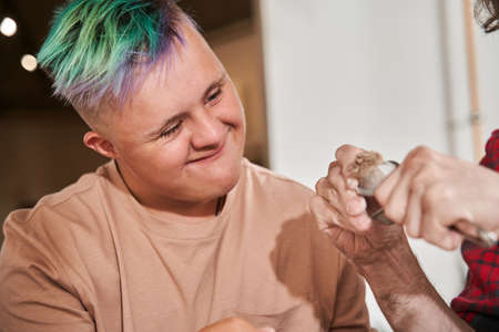 Man with colored hair looking with interest at the equipment at hands of the craftsmanの写真素材