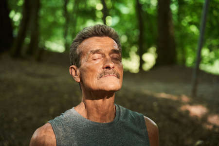Man standing at the forest around the trees and closed his eyes while resting