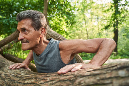 Senior fitness man training push up outside in the forest in summerの写真素材