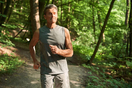 Senior male runner jogging at the park while training outdoors