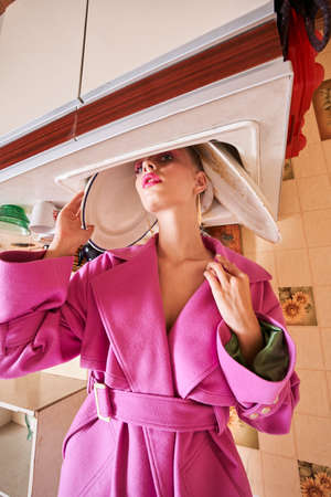 Woman in pink clothes looking at the camera while holding her head at the washbasinの写真素材