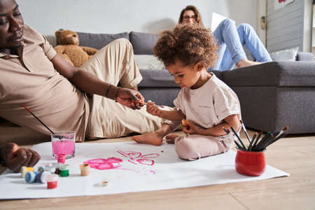 Cute preschool kid girl sitting on the floor and drawing on paperの写真素材