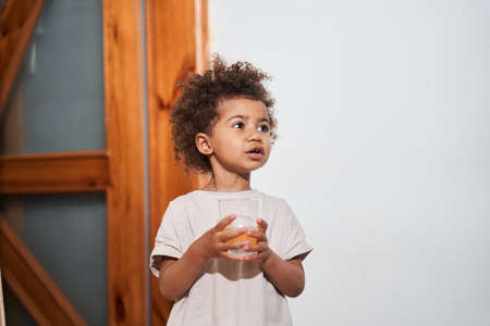 Girl holding glass of juice and talking with somebody while started her morningの写真素材