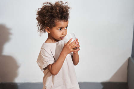 Multiracial girl looking away while drinking juice at the morningの写真素材