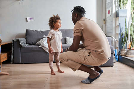 Father and cute little child girl laughing in modern living roomの写真素材