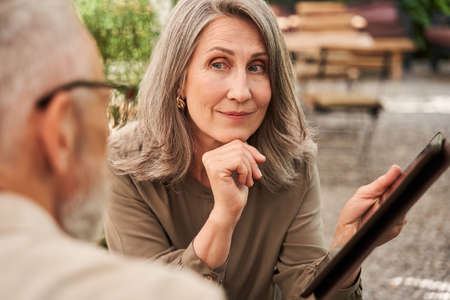 Woman looking at her husband attentively while holding tabletの写真素材