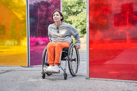 Girl with loss of leg function moving herself with wheelchair while relaxing at natureの写真素材