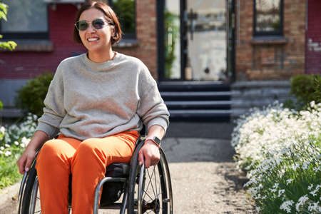 Girl with lower body disability looking away and smiling while enjoying of the summerの写真素材