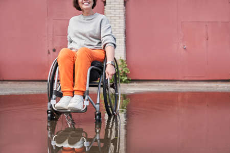 Disabled woman rejoicing of the rainy weather while sitting at the wheelchair and walkingの写真素材