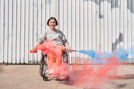 Girl with loss of leg function sitting at wheelchair and playing with bombs with smokeの写真素材