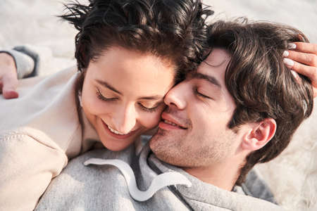 Couple cuddling indoors on the floor at home and laying with eyes closed