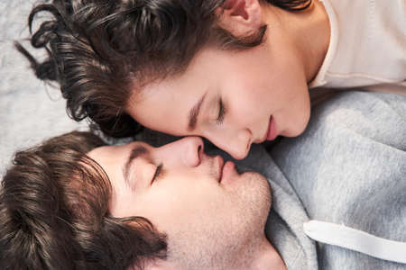 Woman laying with closed eyes and feeling happiness with her manの写真素材