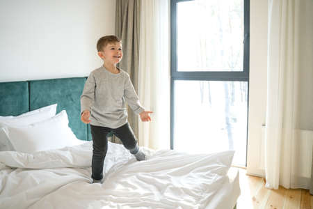 Child standing on bed, playing and laughingの写真素材