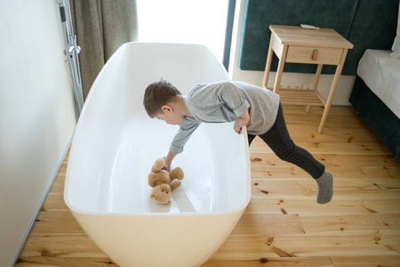Boy playing with his teddy bear at bathroomの写真素材
