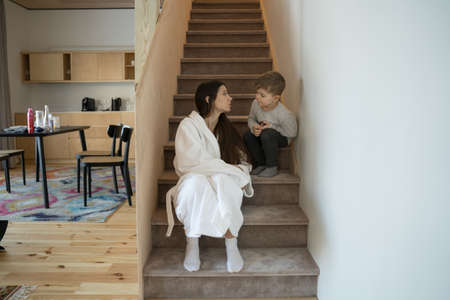 Son and mother chatting with each other while sittingの写真素材