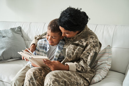 Multiracial woman wearing uniform reading book while sitting at the sofaの写真素材