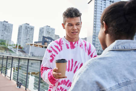 Guy and girl talking on wooden pier in city